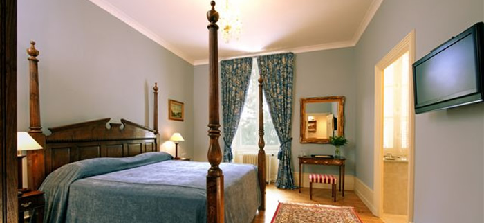 Colonial style bed and other bedroom furniture at Chateau de la Frediere. The furniture was made by the old Bylaw workshop and designed by Graham Hayes.The colour schemes and drapery were created by Brookend Interiors.